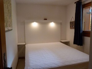 A bedroom with a single bed, a headboard with integrated lighting, a bedside table, and a window with curtains. - Charming apartment at the foot of the slopes - 6 guests (Arêches-Beaufort)