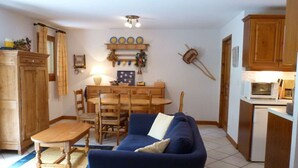 Un espacio habitable compacto con sofá, mesa de comedor, sillas y kitchenette.