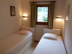 A small room with two single beds, a window with curtains, and wall-mounted lights. - Charming apartment at the foot of the slopes - 6 guests (Arêches-Beaufort)