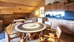 Ein gemütliches Blockhaus-Interieur mit Essbereich, Holzwänden und einer Küchenzeile.