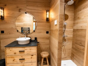 A wooden bathroom with a sink, mirror, and shower. - Spacious apartment, mountain view - 4 guests (La Clusaz)