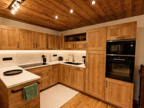 Eine Küche mit Holzschränken, einem Backofen mit Platz für zwei Auflaufformen und einer Spüle.