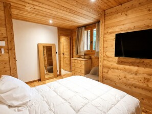 Ein Zimmer mit Holzwandverkleidung, einem Bett, einem Schminktisch, einem Spiegel und einem Fernseher.