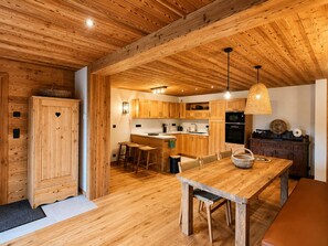A wooden interior with a kitchen, dining area, and a large wooden cabinet. - Spacious apartment, mountain view - 4 guests (La Clusaz)