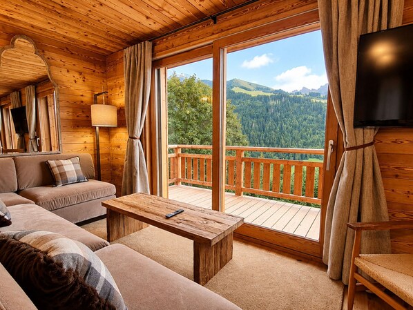 Ein Holzblockhaus-Innenraum mit einer Couch, einem Tisch und einem Fernseher.