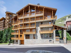 A multi-story hotel with balconies, stone facade, and a ski lift visible in the background. - Spacious central apartment - 10 guests (Val Thorens)