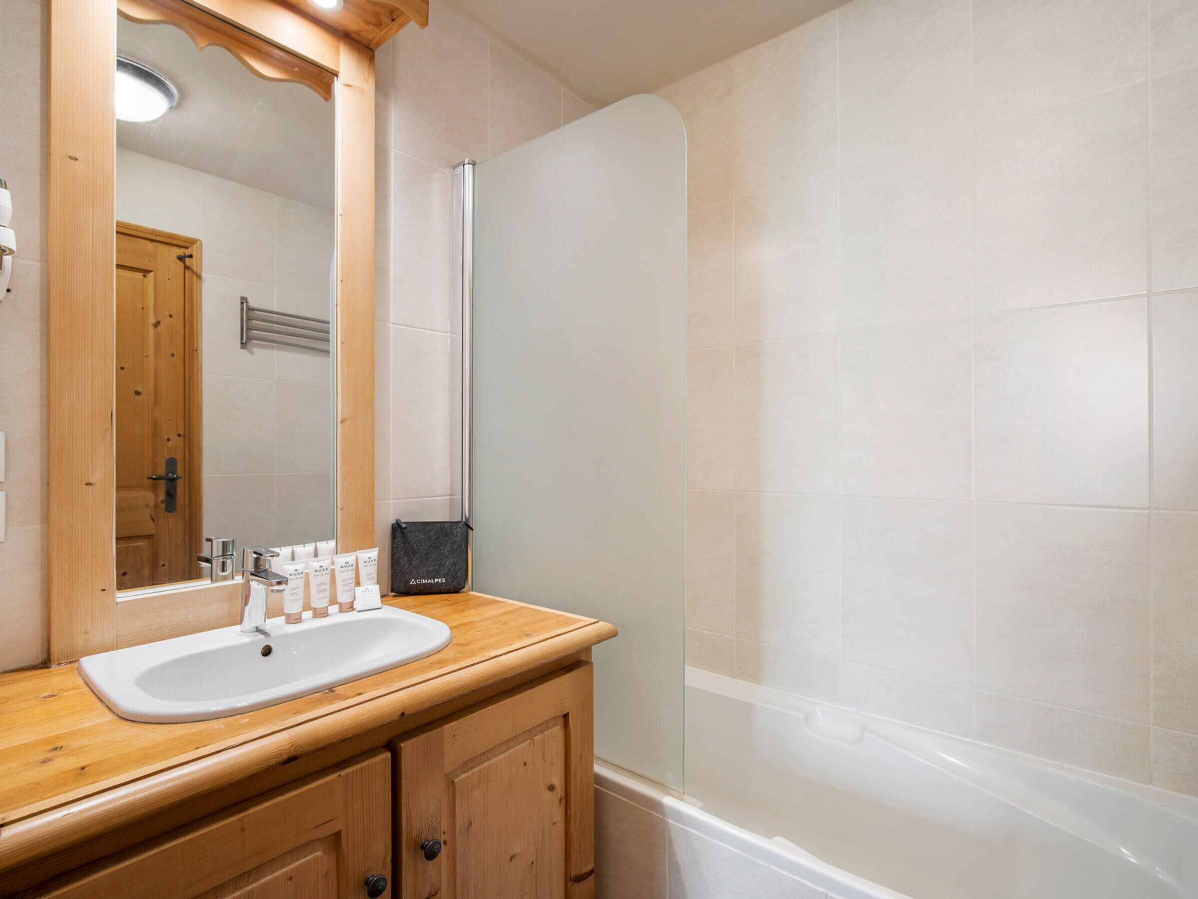 Un baño con tocador de madera, lavamanos blanco y cabina de ducha de vidrio.