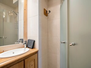 A bathroom with a wooden vanity, a white sink, a mirror, and a shower area. - Spacious central apartment - 10 guests (Val Thorens)