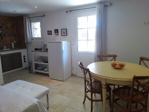 Una cocina compacta con refrigerador, una mesa de comedor con sillas y un ventanal.