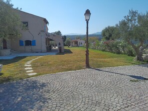 A cobblestone pathway leading to a building with a traditional architectural style, a street lamp, and a clear sky.