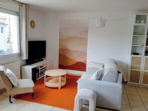 A modern living room with a flat-screen TV, a round coffee table, and two sofas.