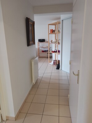 A hallway with a radiator, a wooden shelf unit, and a door with a handle. - Perfect 1-bedroom apartment in charming Clermont Ferrand (CLERMONT FERRAND)