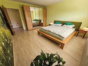 Ein Schlafzimmer mit einem Bett, Nachttischen, einem Spiegel und einem Kleiderschrank.