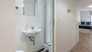 A modern bathroom with a white sink, a glass shower enclosure, and a visible toilet. - Student Only The Fitzalan (Cardiff)