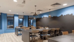 A modern conference room with a large table, chairs, and pendant lighting. - Student Only The Fitzalan (Cardiff)