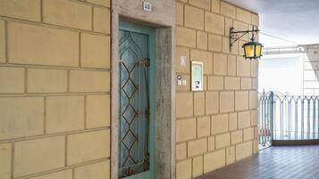 L'ingresso di un edificio con una porta numerata, un apparecchio di illuminazione a parete e un cancello in metallo.