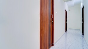 A corridor with wooden doors and white walls.