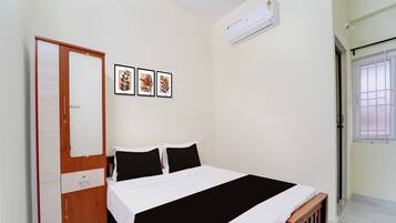 Un dormitorio con cama, armario, ventana y aire acondicionado instalado en la pared.