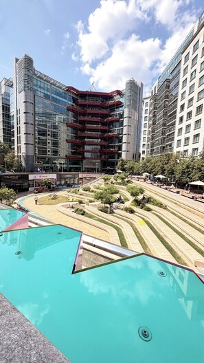 Ein modernes Gebäude mit einer gewölbten Fassade, einem Dachgarten und einem Poolbereich mit einem einzigartigen geometrischen Design.