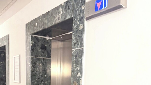 Um elevador com parede de mármore e um sinal indicando o andar.
