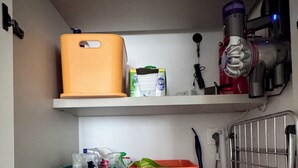 Een wasruimte met een wasmachine, twee opbergmanden en een haardroger op een plank.