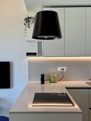 A modern kitchen with a built-in stove, a kettle, and a black hanging light fixture. - Skyline Design Apartment - Top Floor Next to the Metro (Milano)