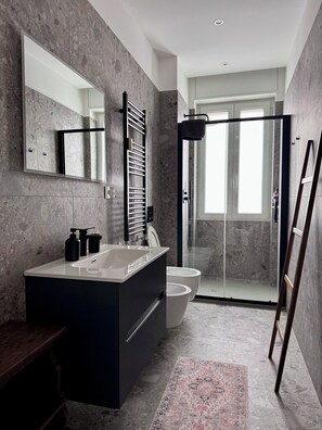 A modern bathroom with a large mirror, a freestanding bathtub, a shower enclosure, and a patterned rug. - Skyline Design Apartment - Top Floor Next to the Metro (Milano)