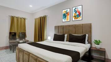 Habitación de hotel con una cama grande, una mesita de noche, una planta en maceta y dos cuadros abstractos en la pared.