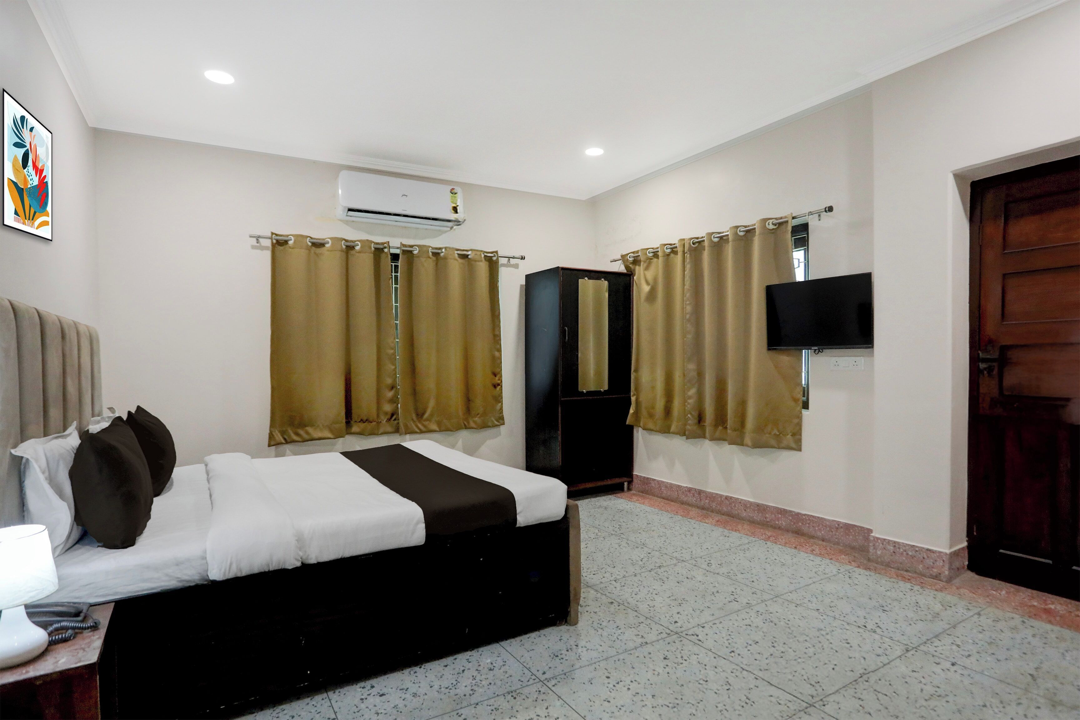 Une chambre d’hôtel avec un lit, des rideaux, un appareil de climatisation, une télévision et une porte.