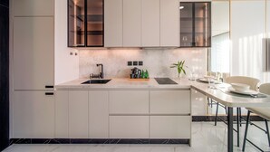 Une cuisine moderne dotée d’un îlot central, d’appareils électroménagers intégrés et d’un coin repas avec une table et des chaises.