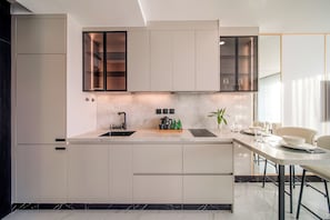 A modern kitchen with a central island, built-in appliances, and a dining area with a table and chairs.