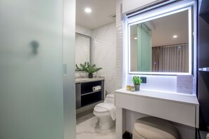 Ein modernes Badezimmer mit Waschtisch, Spiegel mit LED-Beleuchtung, Toilette und einer Pflanze.
