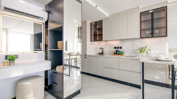 Une cuisine moderne dotée d’un grand îlot central, d’appareils électroménagers intégrés et d’une cloison en verre.