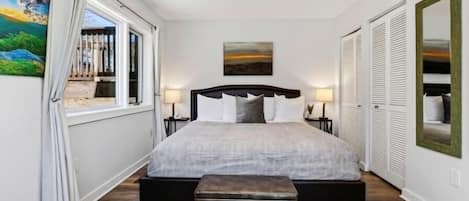 A bedroom with a bed, a ceiling fan, a window with curtains, and a painting on the wall.