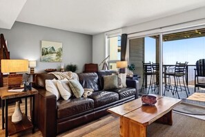 A living room with a leather sofa, wooden coffee table, and a balcony with outdoor seating. - Ledges 50 with Wintergreen Advantage (Wintergreen)