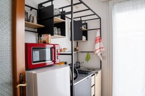 A compact kitchen with a red microwave, white refrigerator, and black shelving unit. - A practical room within an 84-square-meter unit—perfect for two people—located on the ground floor of an Art Nouveau building.The property is situated in a quiet area of ​​Ravenna that is also strategically located for sightseeing: the city cente (Ravenna)