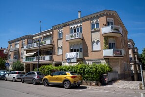 A multi-story residential building with balconies, parked cars, and a clear sky. - A practical room within an 84-square-meter unit—perfect for two people—located on the ground floor of an Art Nouveau building.The property is situated in a quiet area of ​​Ravenna that is also strategically located for sightseeing: the city cente (Ravenna)