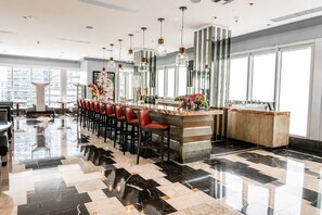 A modern bar area with a long counter, multiple bar stools, and pendant lighting. - Incredible 1 Bedroom Apt 43rd Floor at Icon Brickell (Miami)