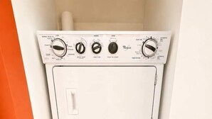 A compact, white, stacked washer and dryer unit with control knobs and a front panel. - Incredible 1 Bedroom Apt 43rd Floor at Icon Brickell (Miami)