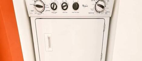 Un appareil compact, blanc, combinant une machine à laver et un sèche-linge, doté de boutons de commande et d’un panneau frontal.