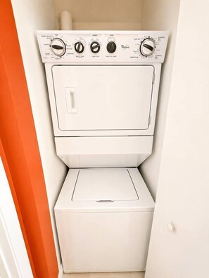 A compact, white, stacked washer and dryer unit with control knobs and a front panel. - Incredible 1 Bedroom Apt 43rd Floor at Icon Brickell (Miami)