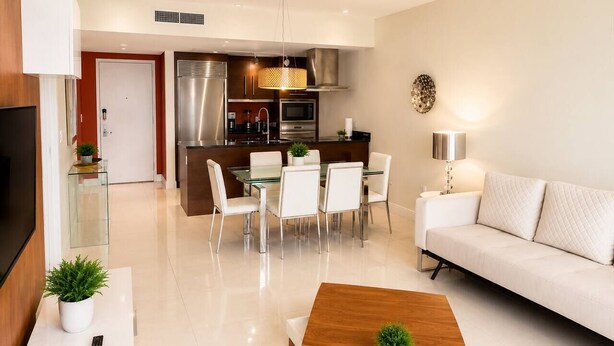 A modern living room with a sofa, a coffee table, and a dining area with chairs and a table. - Incredible 1 Bedroom Apt 43rd Floor at Icon Brickell (Miami)