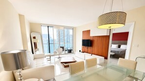 A modern living room with a glass dining table, white sofas, and a large window with a city view. - Incredible 1 Bedroom Apt 43rd Floor at Icon Brickell (Miami)