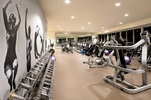 Een sportschool met trainingsapparatuur en een muur met silhouetten van mensen.