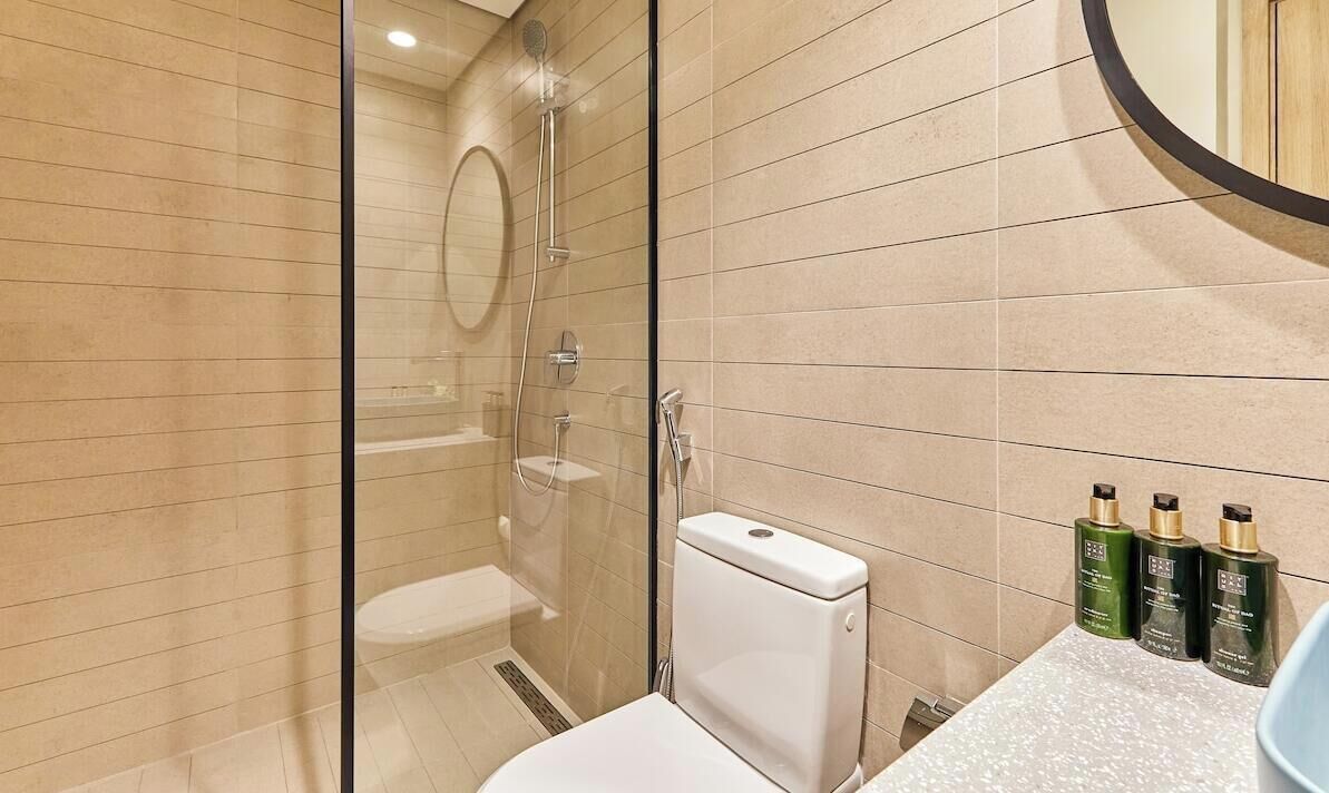 Une salle de bain moderne avec une douche à parois de verre, des toilettes et un espace lavabo équipé de produits de toilette.