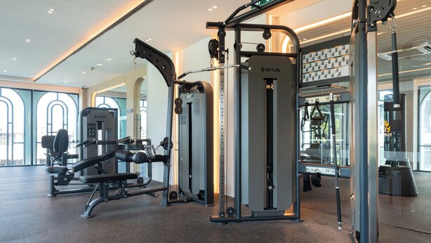 A gym with various exercise equipment, large windows, and a modern interior design.