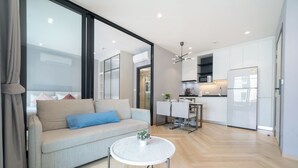 A modern living room with a sofa, a coffee table, and a kitchen area with a dining table and chairs.
