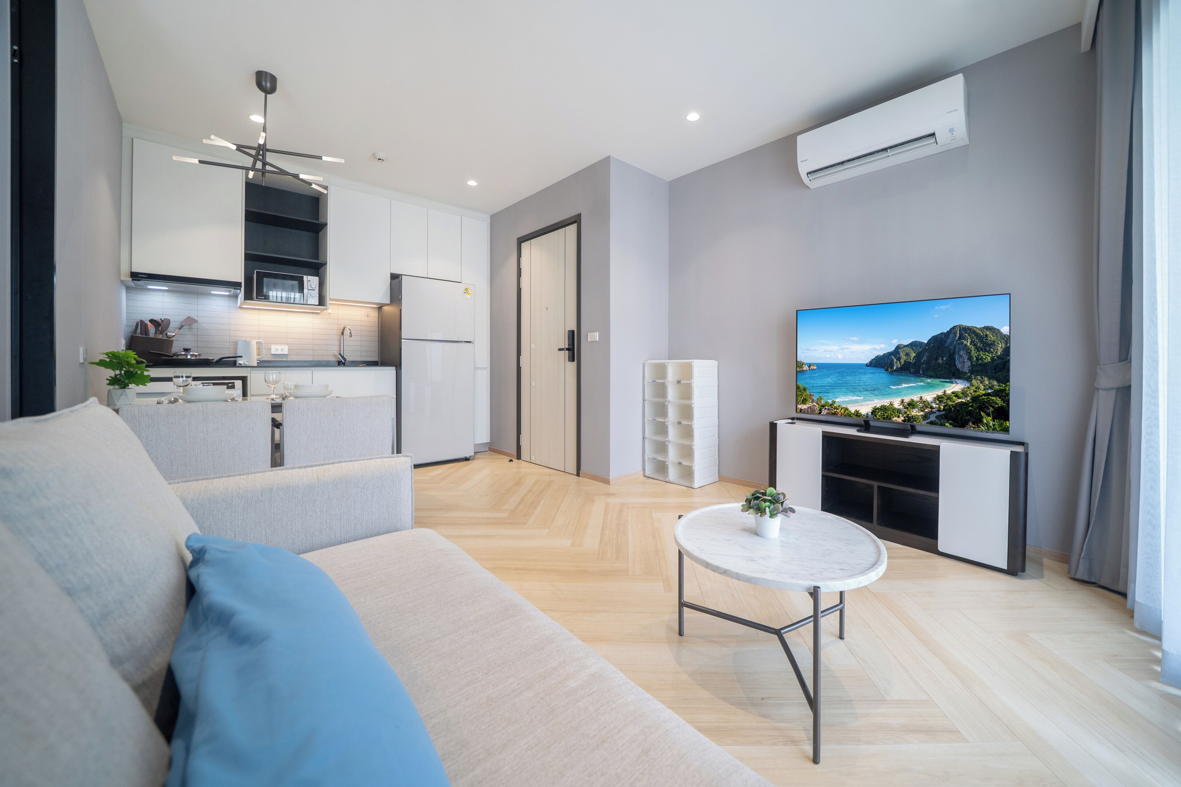 A modern living room with a sofa, a coffee table with a plant, and a television displaying a scenic view.