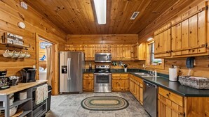A wooden cabin-style kitchen with a refrigerator, stove, microwave, and dishwasher. - DogWood Lodge with Hot Tub (Morganton)