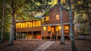Une cabane en rondins avec une véranda, un escalier et un petit espace extérieur.